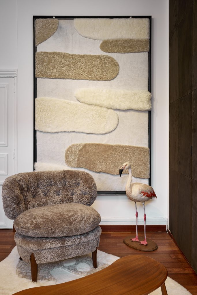 Comme une œuvre d'art murale, notre tapis Betula en peau de vache et peau de mouton est exposé devant un fauteuil Otto Schulz. Ces créations d'exception aux finitions haute couture fabriquées en France sont disponibles sur mesure sous 6 semaines.